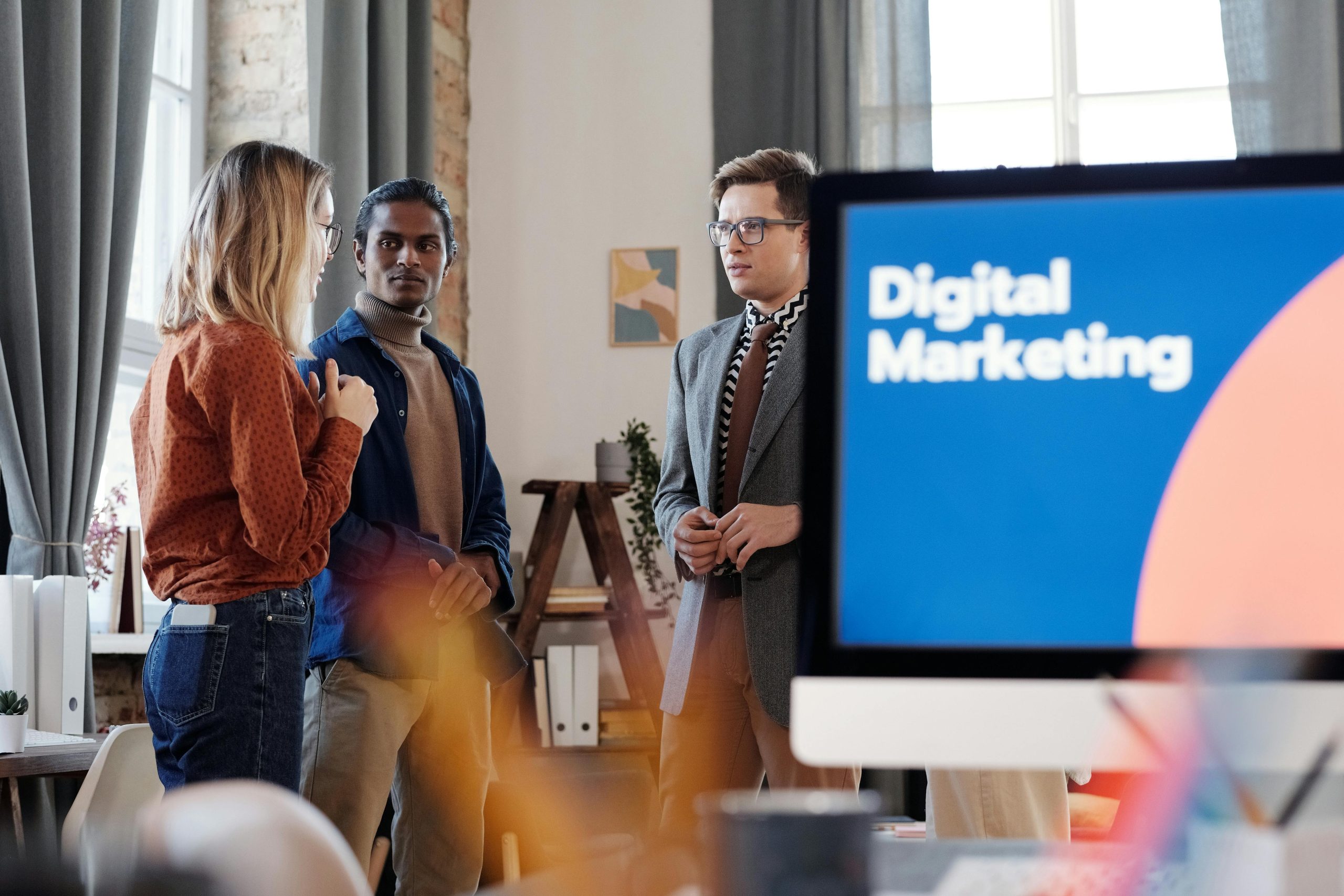 About Group of colleagues discussing digital marketing strategies in an office setting.